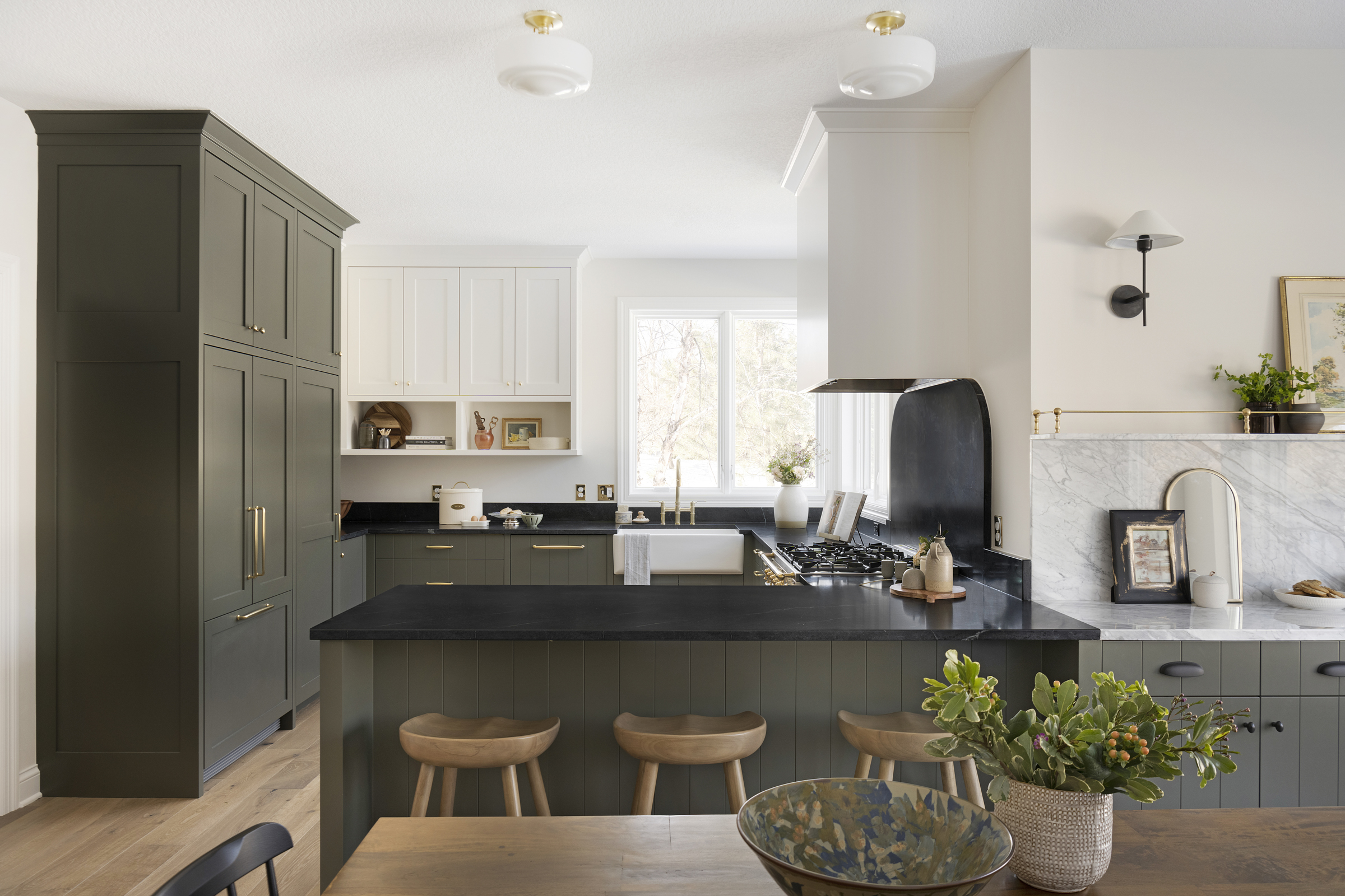 Two tone kitchen cabinetry with natural soapstone countertops, La Carnue range, brass details.