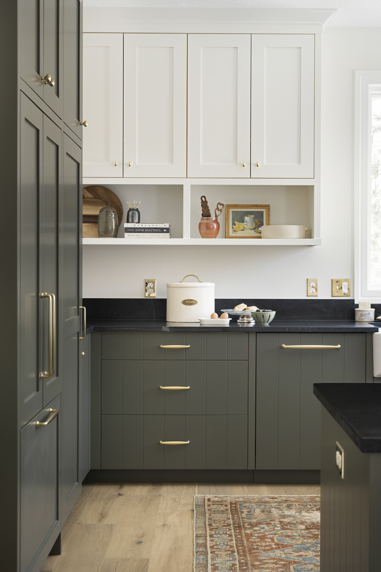 Two tone kitchen cabinetry with natural soapstone countertops, brass details.