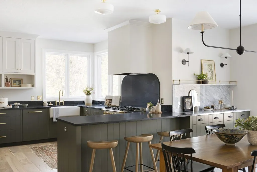 Two tone kitchen cabinetry with natural soapstone countertops, La Carnue range, brass details.