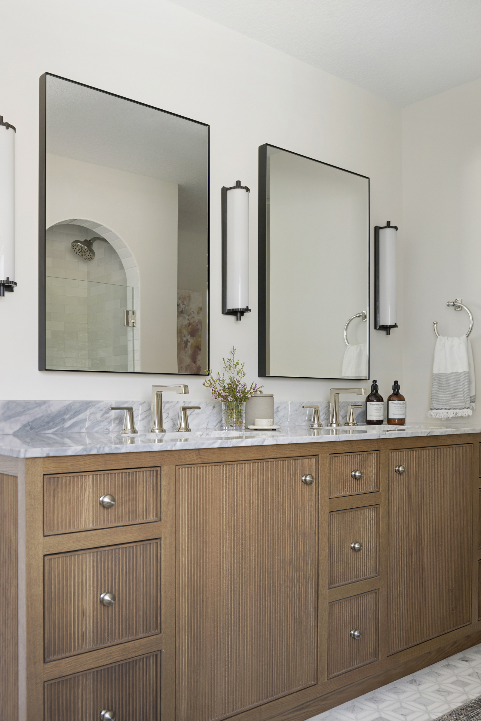 primary suite reeded oak bathroom vanity, natural marble countertops.