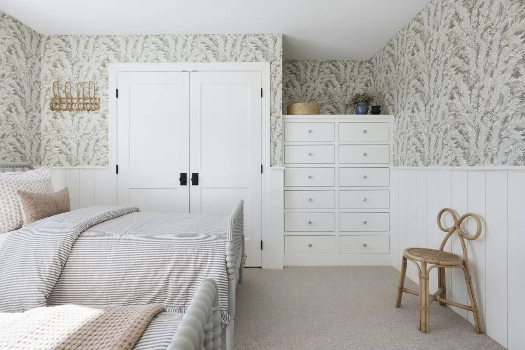 Guest bedroom with custom inset built in cabinetry, floral wallpaper and twin beds.