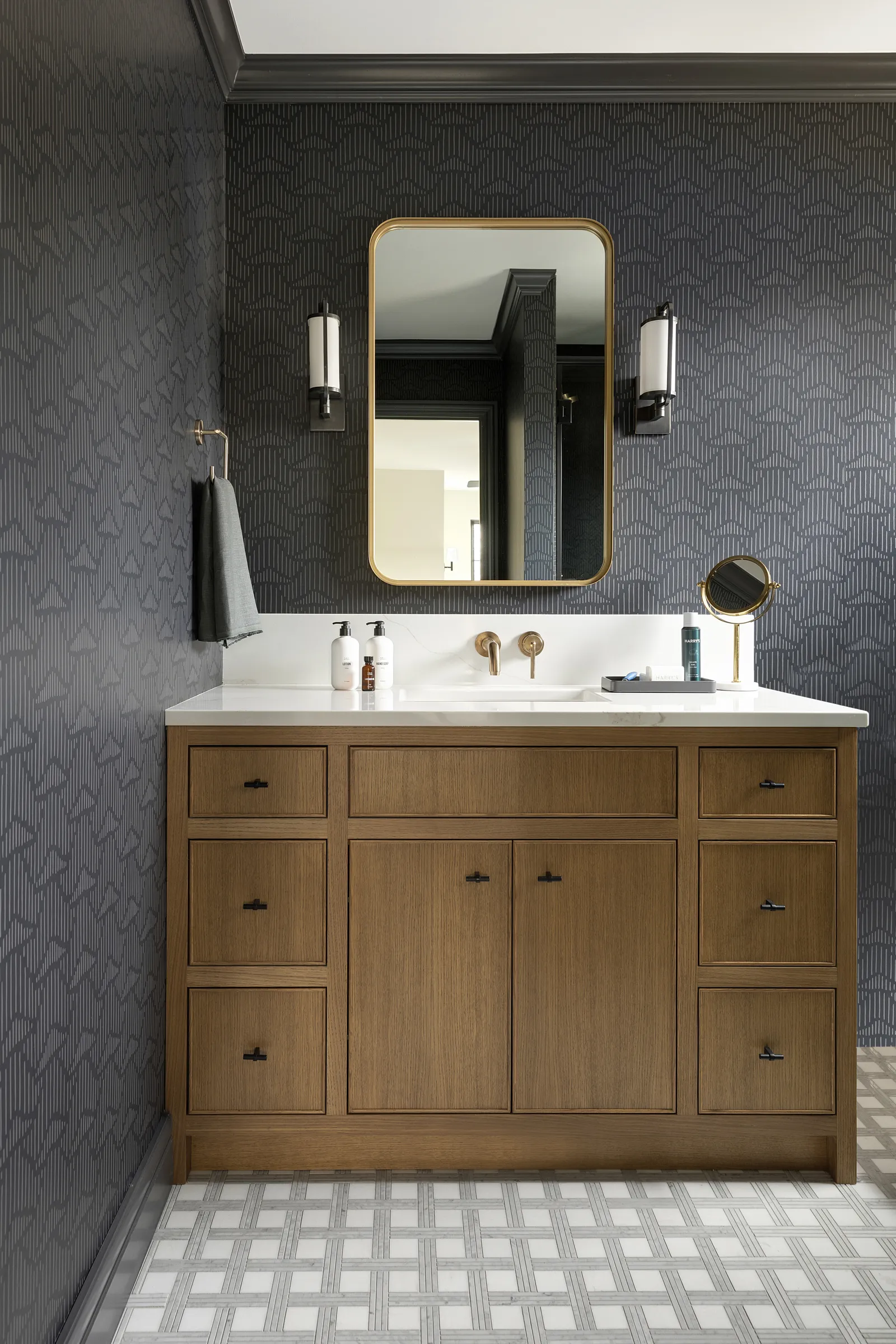 White oak inset bathroom vanity with brass wall mount faucet and cool geometric black wallpaper