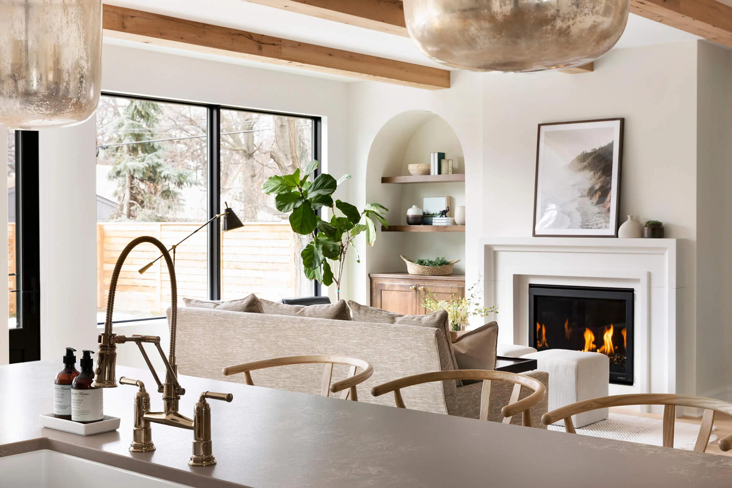 Black picture window, gas fireplace, arched built in custom bookcase, and white oak engineered hardwood floor