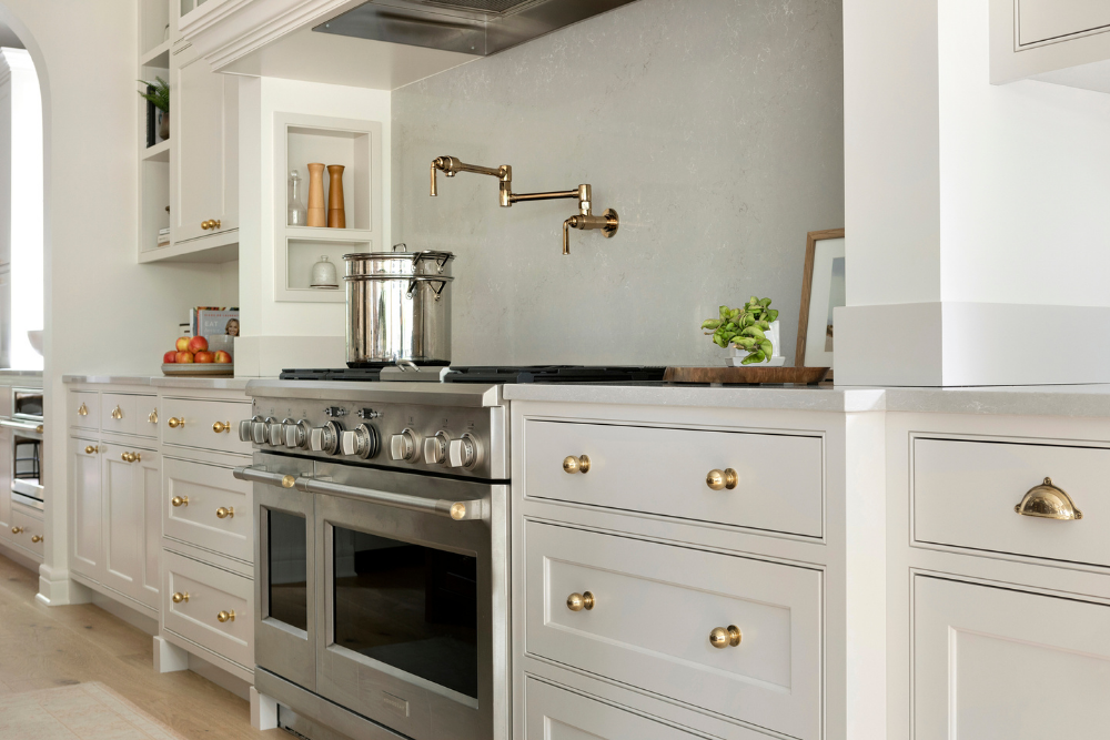 Kitchen with range alcove, custom cabinets, brass hardware, and pot filler.