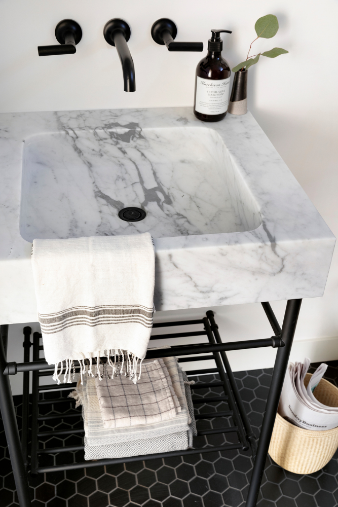 Marble console sink with black legs and plumbing fixtures.