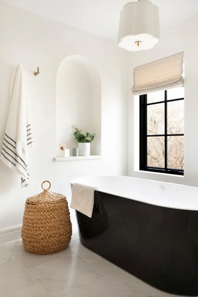 Primary bathroom with arched niche and black freestanding tub.