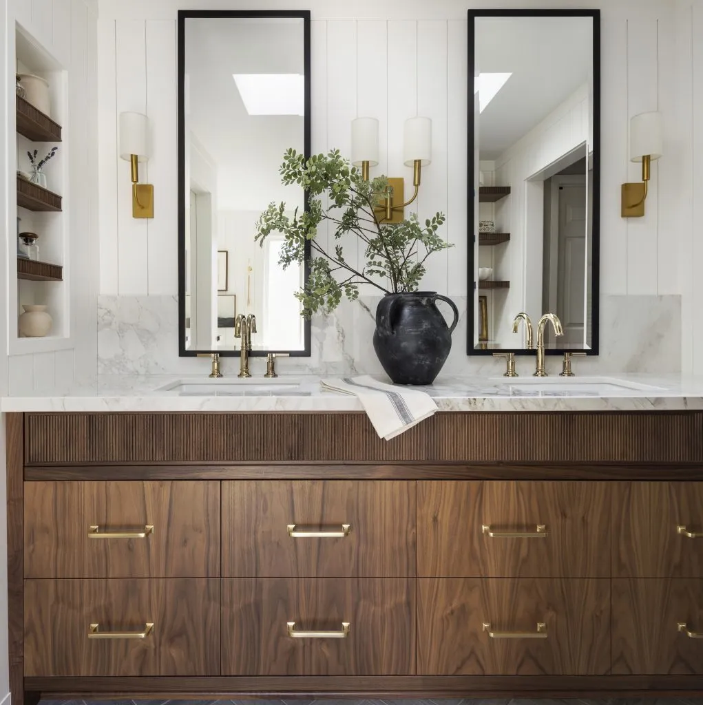 Custom walnut bathroom vanity, reeded details, limestone tile flooring and polished brass accents.