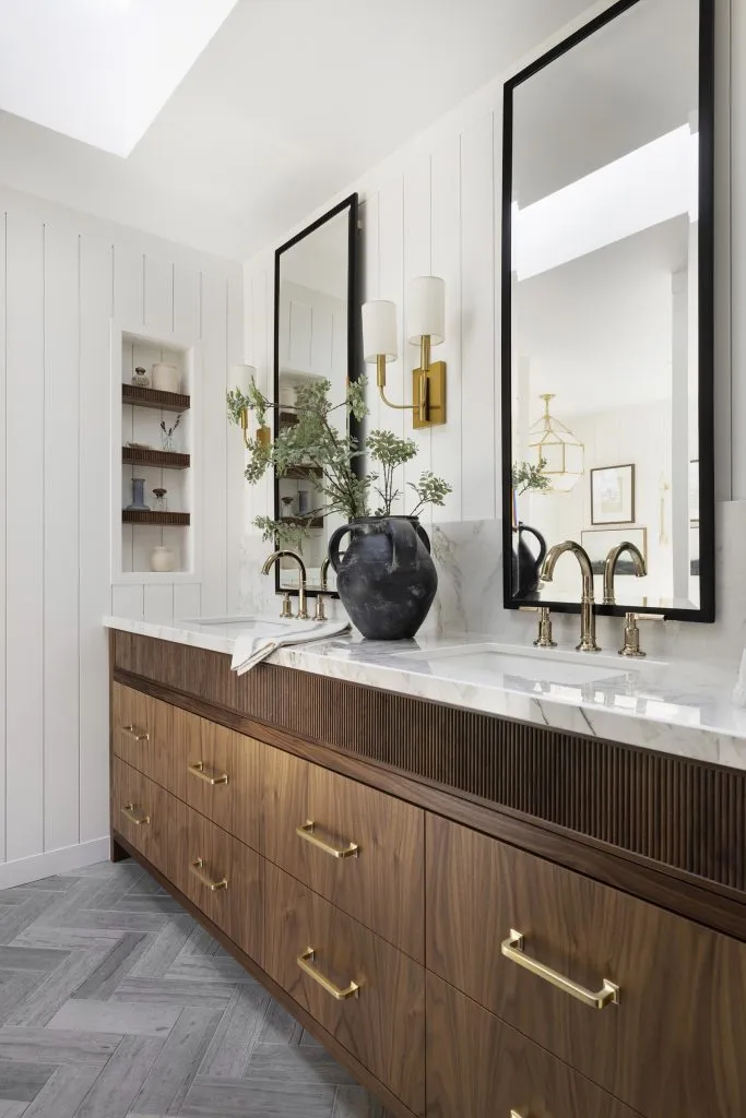 Custom walnut bathroom vanity, reeded details, limestone tile flooring and polished brass accents.