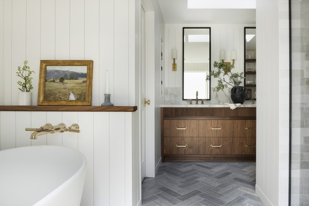 Custom walnut bathroom vanity, reeded details, limestone tile flooring and polished brass accents.