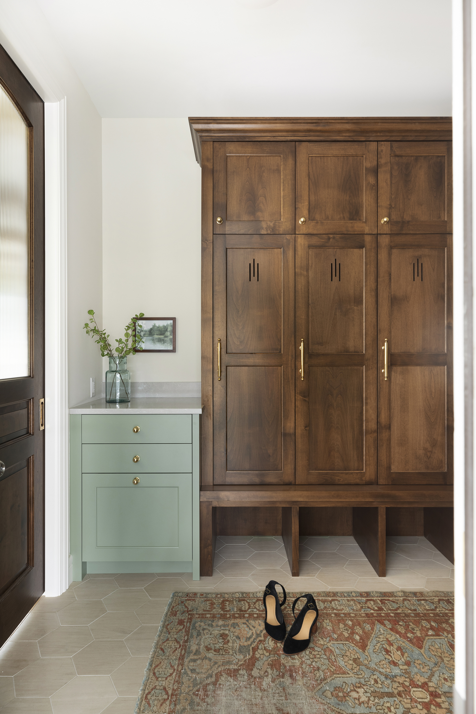 Custom alder mudroom cabinetry storage with Tudor style cut out detail