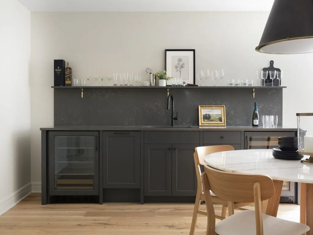 Basement bar with panel ready appliances, quartz backsplash and open shelf with brass brackets.