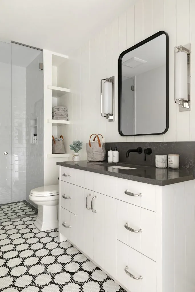 Custom bathroom vanity with black countertop with black and white glass mosaic floor tile