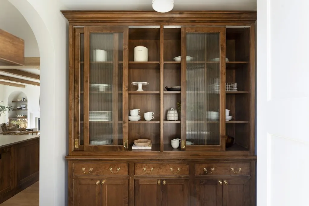 Custom alder pantry hutch with sliding reeded glass doors and burnished unlacquered brass hardware
