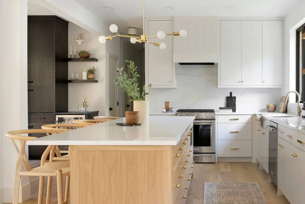 Custom light and bright kitchen cabinets with white oak island and off-white perimeter cabinets with quartz countertop and modern island pendant, white oak wishbone counter stools