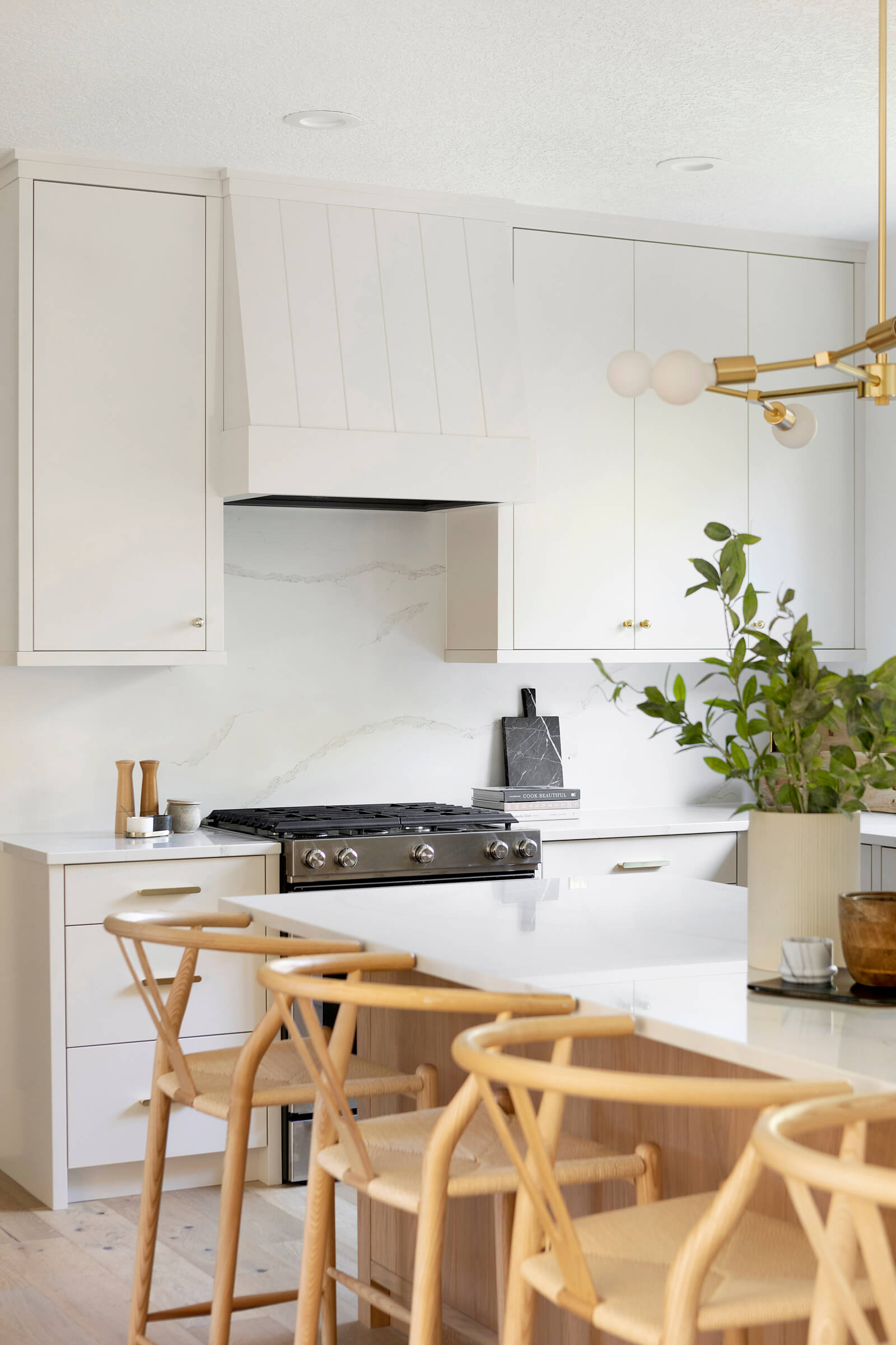Sherwin Williams Limewash custom modern slab kitchen cabinetry with paneled range hood, quartz countertops and backsplash and white oak kitchen island counter stools