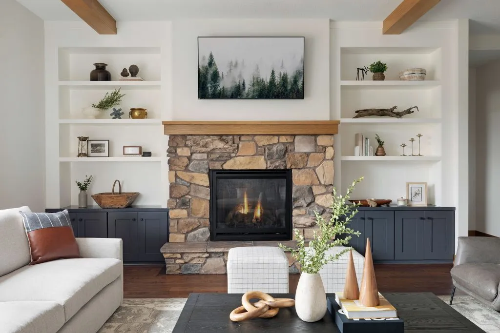 Natural stone fireplace with white oak beams and mantel with black cabinets and white floating shelves