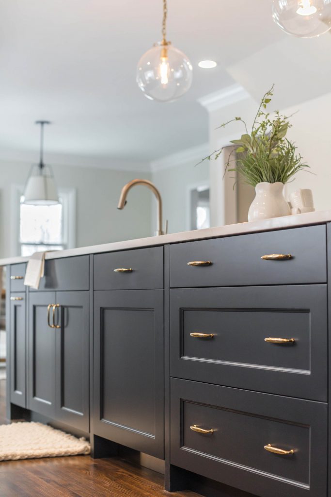 Custom dark blue island cabinetry with brass hardware pulls