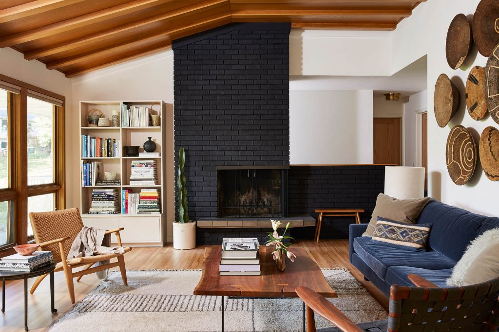 Black painted brick fireplace with white oak ceiling beams in mid-century modern home