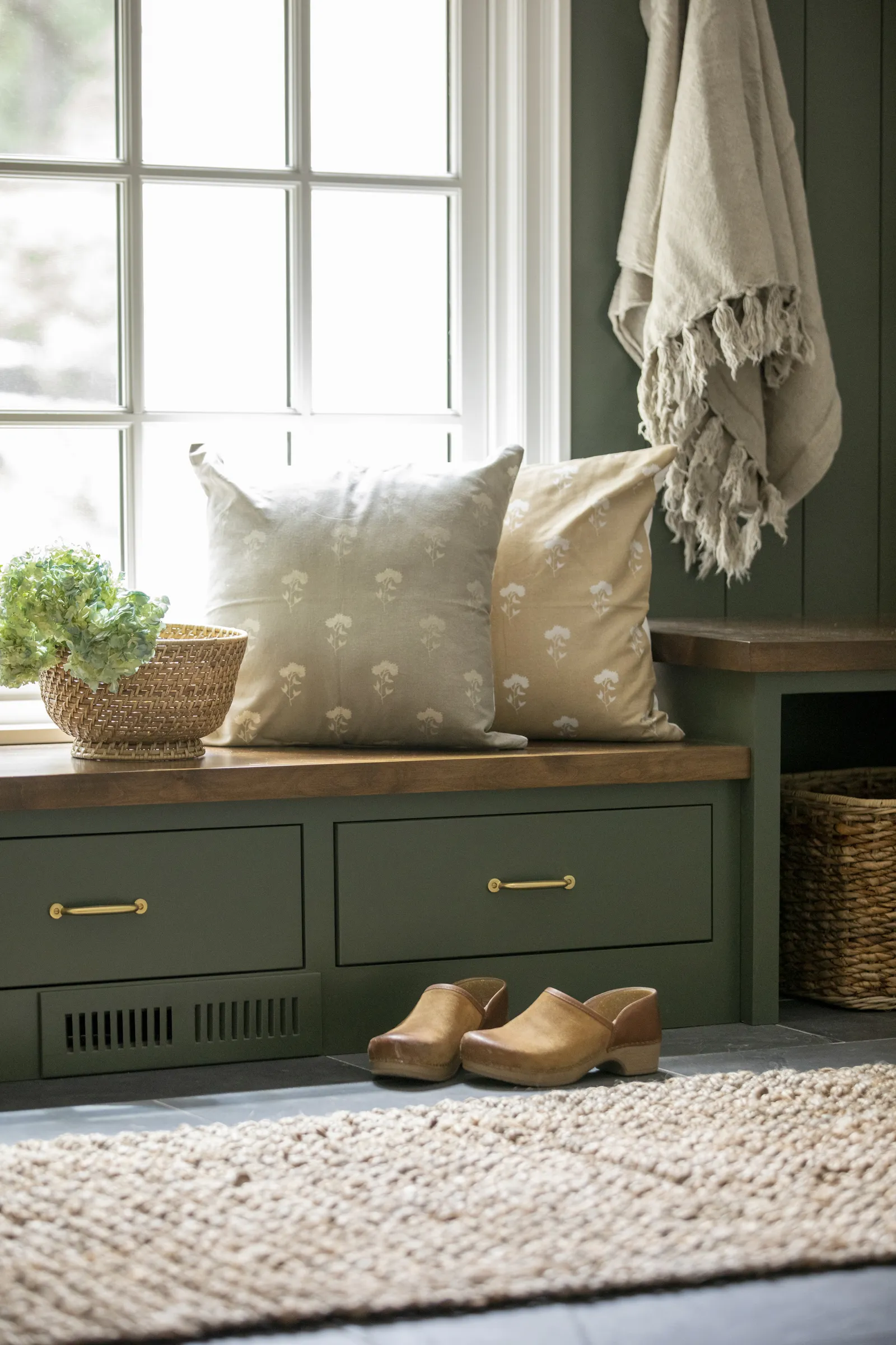 Green mudroom cabinetry, brass hardware, open storage.