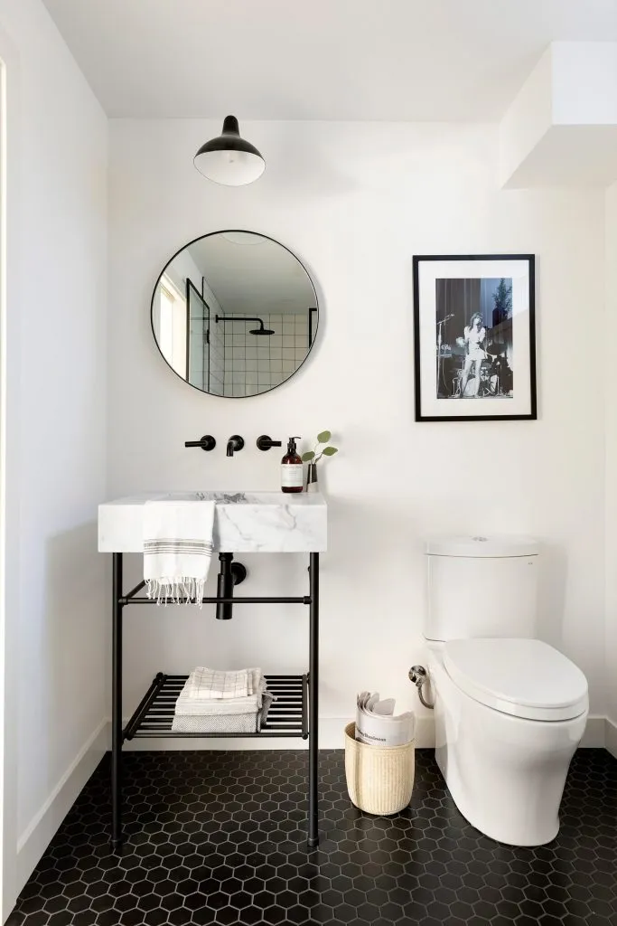 Custom black and marble console vanity with wall mount black faucet with black hexagon floor tile and modern light fixture