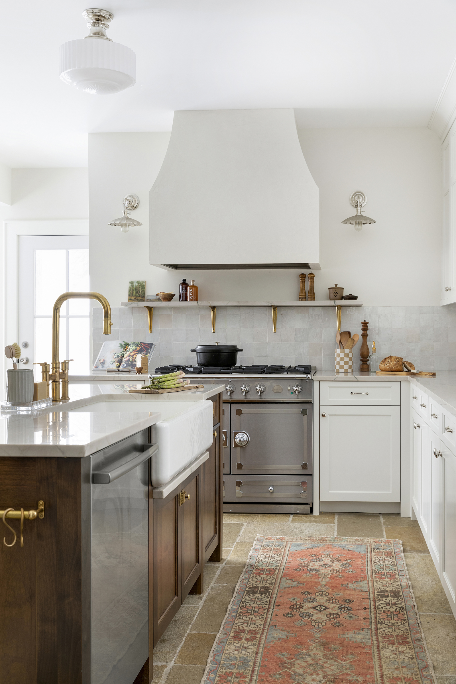 French cafe inspired kitchen with plaster hood detail, unlacquered brass, lacornue range, quartzite countertops and natural limestone pavers.