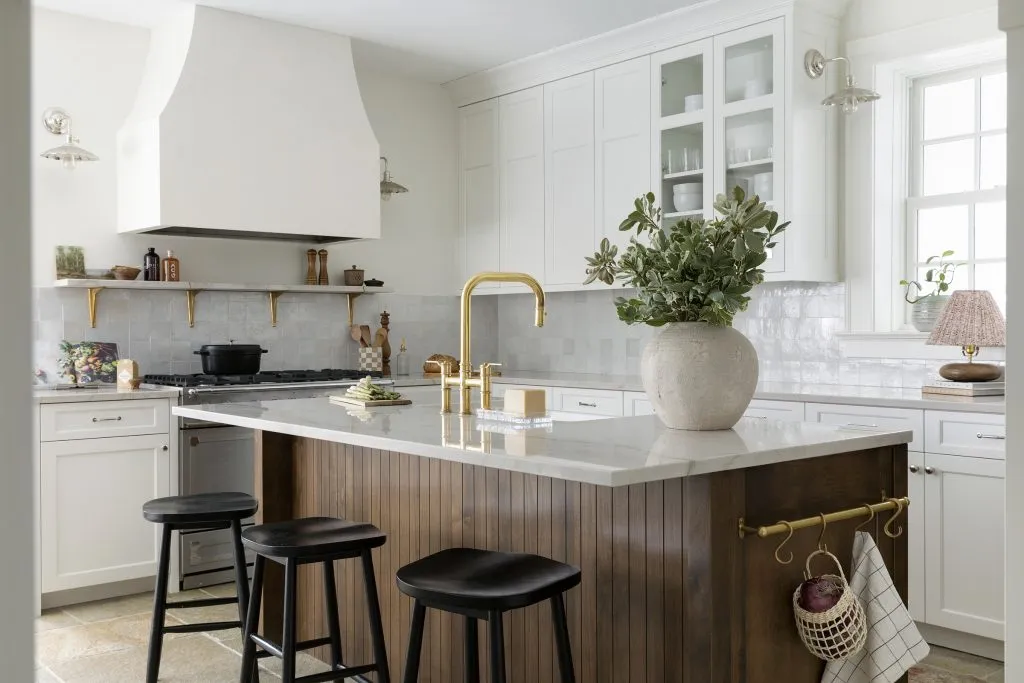 French cafe inspired kitchen with plaster hood detail, unlacquered brass, lacornue range, quartzite countertops and natural limestone pavers.