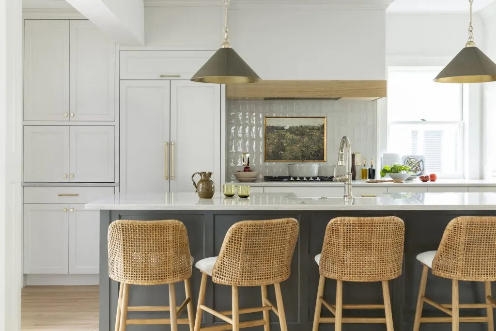 How to Refresh a 1920s Home, While Mixing Modern and Traditional Design Styles. Natural red oak floors, off white cabinetry with dark painted island, apron sink with stone drip ledge and mixed metals.