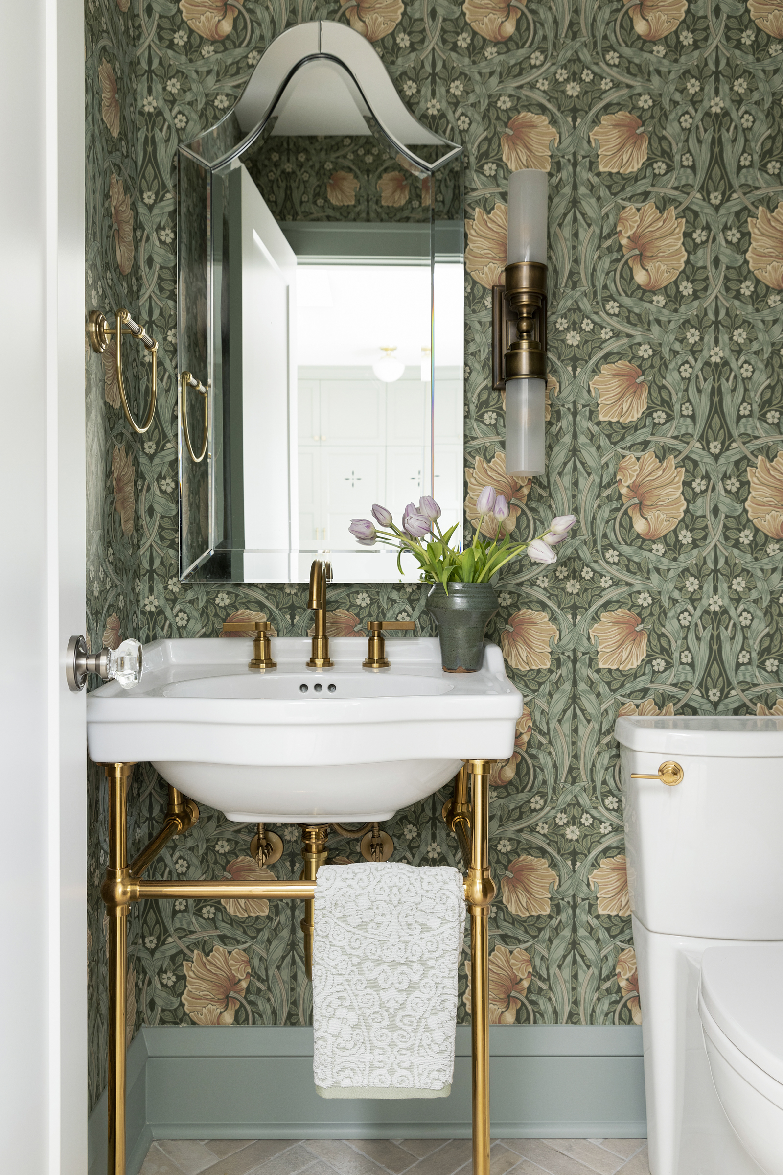 Twin Cities powder room renovation with green floral wallpaper, console sink, and brass accents.