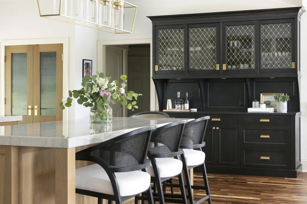 Dark black kitchen hutch, solid brass cabinet hardware, and mesh grill cabinetry inserts.