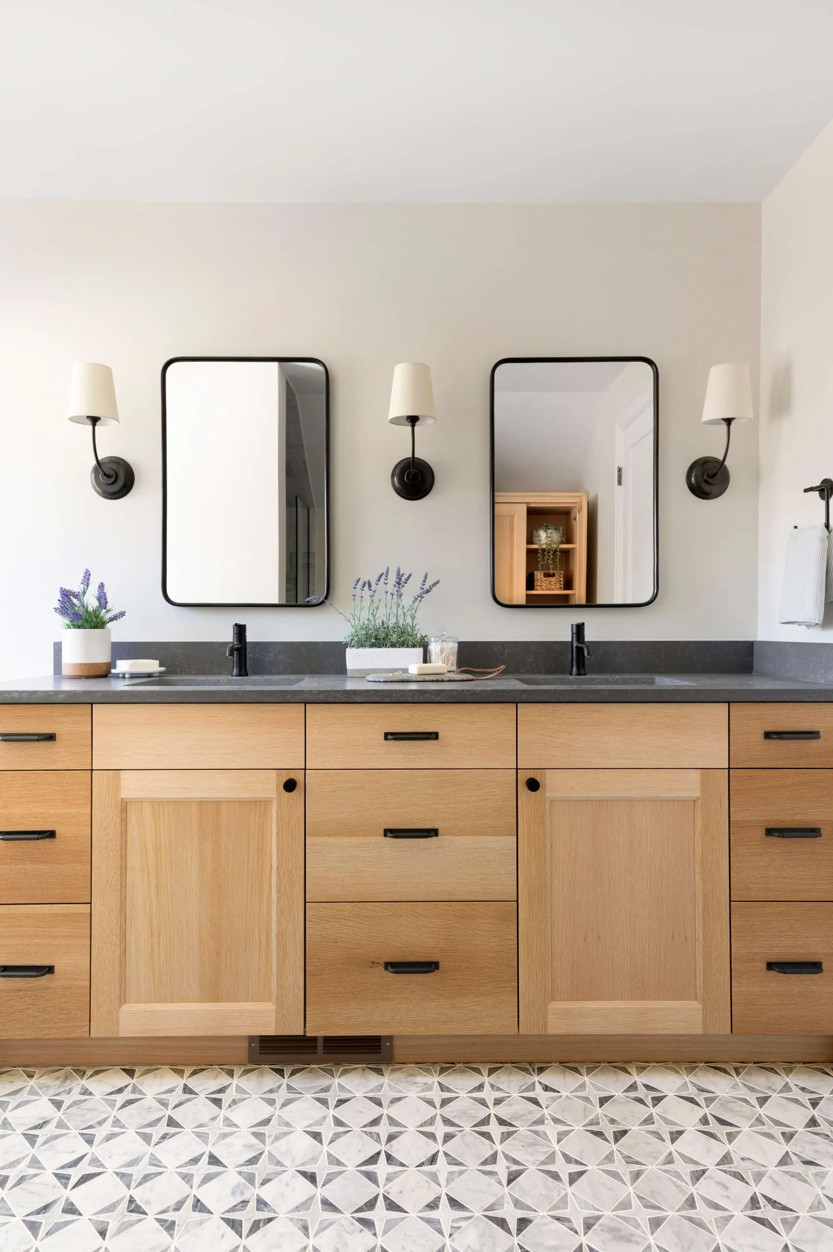 White oak double vanity with dark quartz countertop, marble mosaic floor tile and black accents. Dean vanity